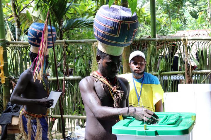  Figure 2: A man wearing an //upe// casts a ballot in the 2019 Bougainville independence referendum at the all-male polling place at Kunua on November 29, 2019 (“Upes Come Out to Cast Their Vote” 2019).